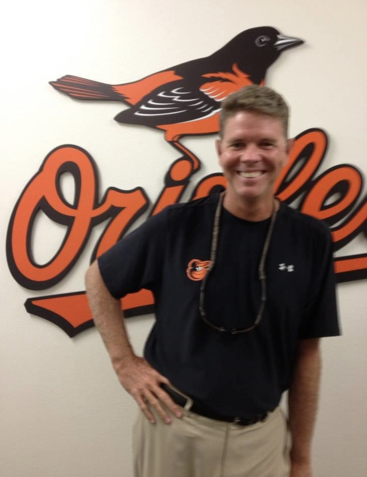 Joel D. Bradley standing in front of the Baltimore Orioles logo